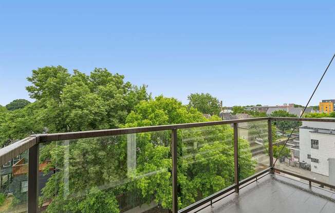 A balcony with a metal railing overlooks a lush green forest.