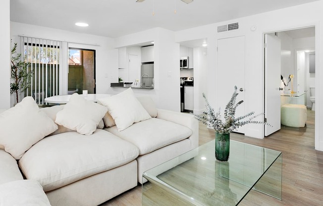 A modern living room with a white couch and a glass coffee table.