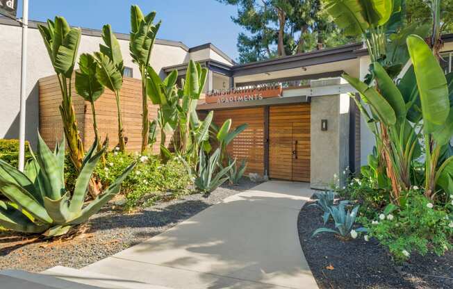 the front of a building with a sidewalk and plants