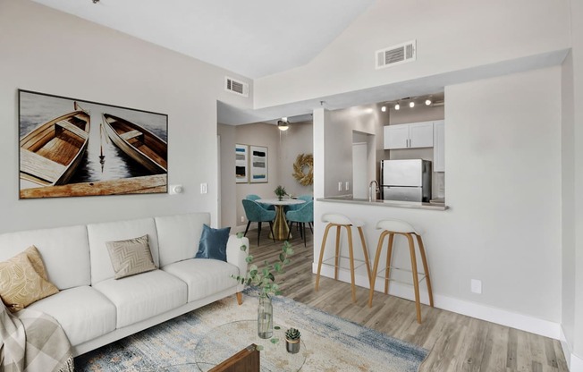 A living room with a white couch and a painting of boats on the wall.
