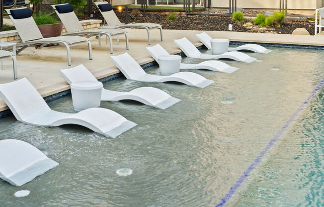 A pool with white chairs and a blue line in the middle.