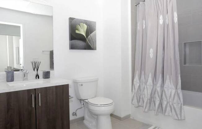 a white bathroom with a toilet and a shower curtain