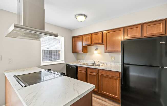 A kitchen with a black refrigerator and wooden cabinets.