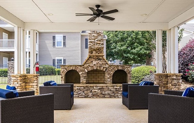 a covered patio with a stone fireplace and chairs at Bedford Parke Apartments, Warner Robins, GA 31088