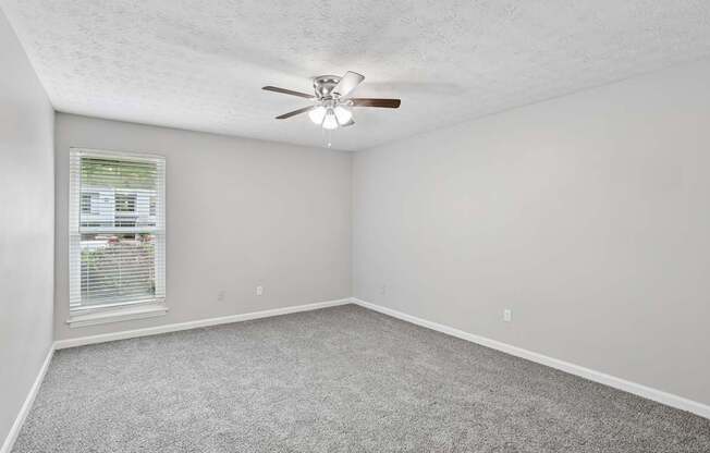 A room with a ceiling fan and carpeted floor.