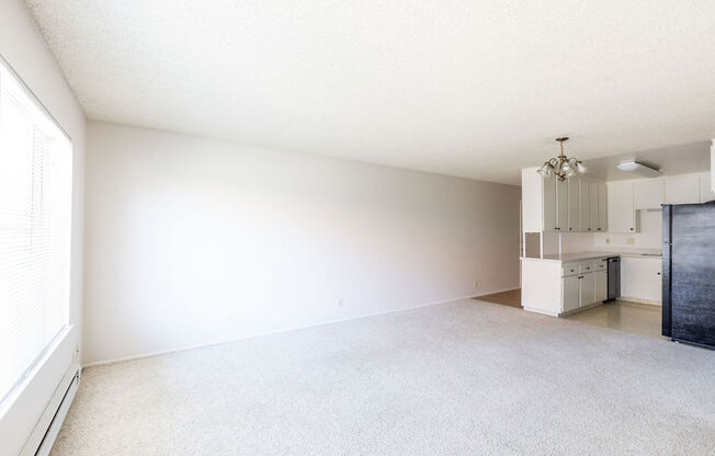 an empty living room and kitchen with a large window