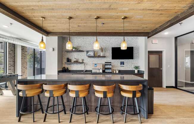 a kitchen with a large island with four stools and a tv on the wall at EagleRidge Plaza Residences, North Dakota