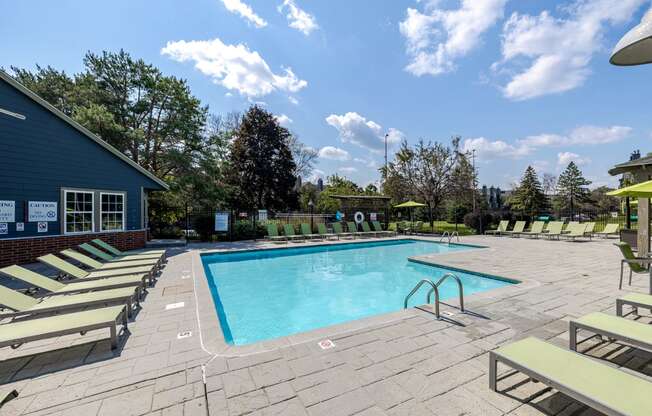 the resort style pool is surrounded by lounge chairs and a blue building