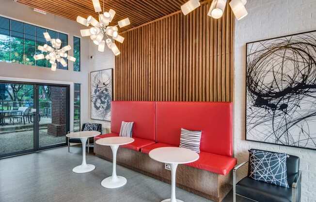 A modern cafe with a red booth and white tables.