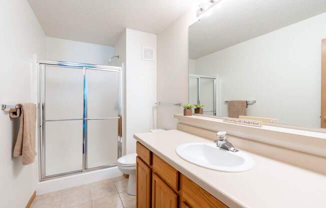 A bathroom with a sink, toilet, and shower. Fargo, ND Stonebridge Apartments