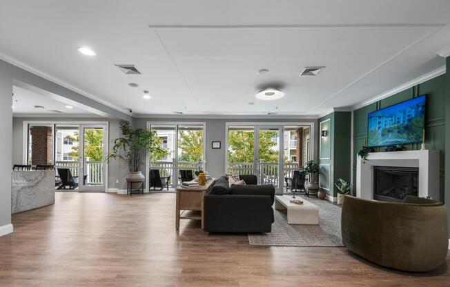 Resident clubhouse lounge with a fireplace, comfortable seating, and expansive windows that create an inviting setting for gathering, relaxation, and conversation.