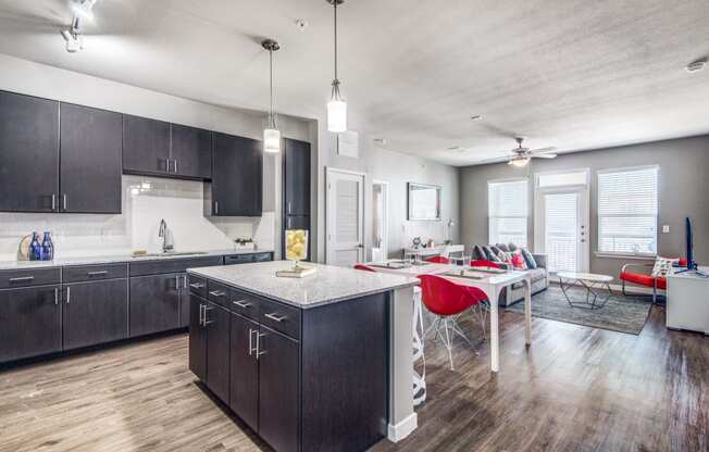 a kitchen and living room with dark cabinets and a white table with red chairs