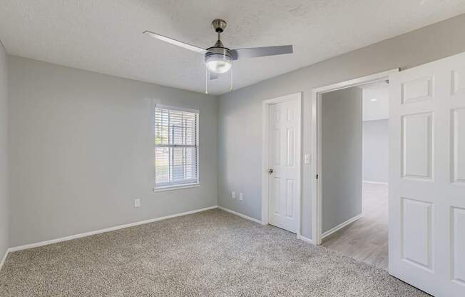 A room with a ceiling fan and a window.