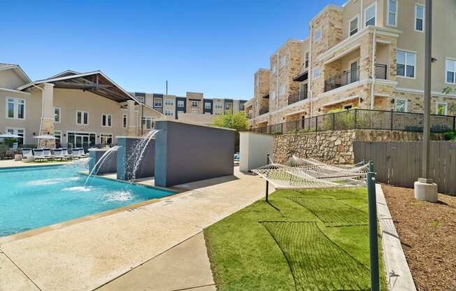 A swimming pool with a slide and a building in the background.