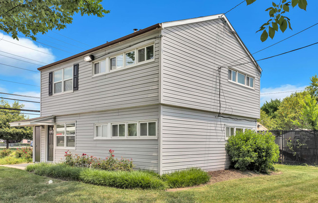 the back of a gray house with white siding and a yard with grass