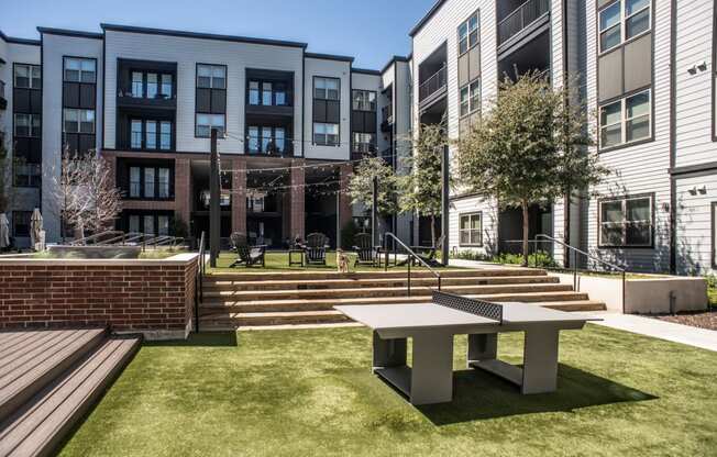 a patio with a table and benches in front of some buildings