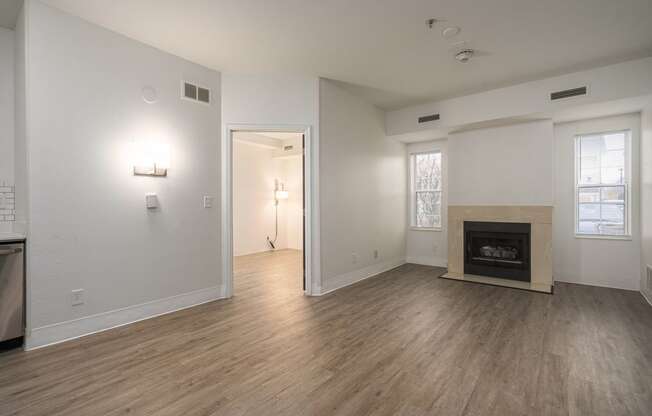 an empty living room with a fireplace and wood flooring