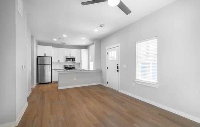 an empty living room and kitchen with white walls and wood floors