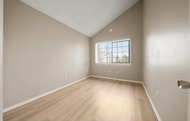 Empty room with a window and wooden flooring.