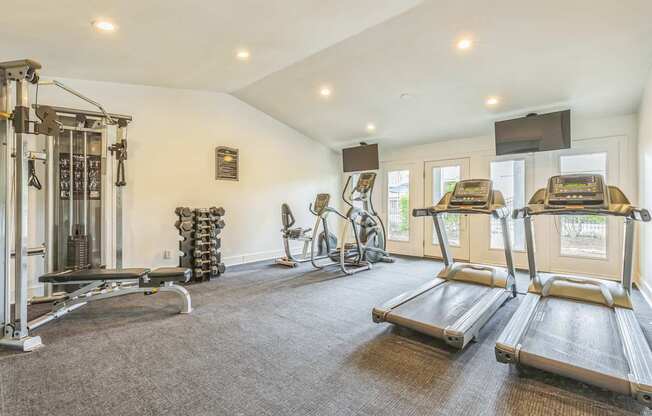 A spacious home gym with treadmills, weights, and exercise equipment.