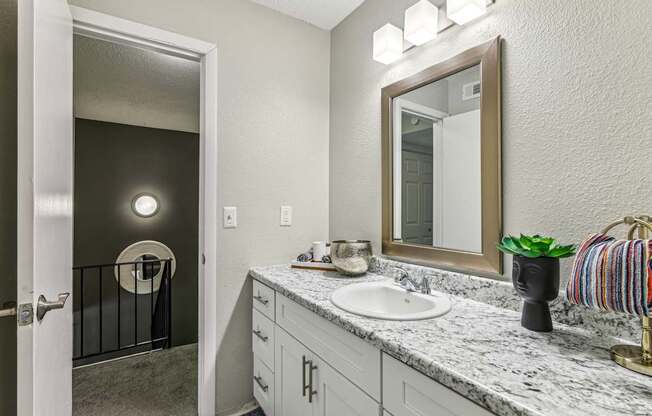 A bathroom with a sink, mirror, and a striped towel.