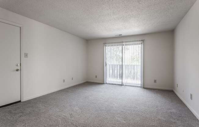 an empty bedroom with a door leading to a balcony