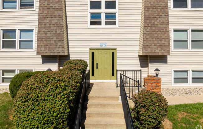 the front of a white house with a green door