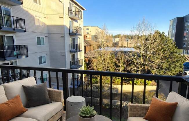 A balcony with a sofa, chairs and a table with a potted plant on it.