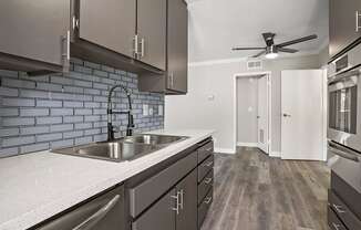 Blue tiled kitchen with stainless steel oven, microwave, and fixtures.