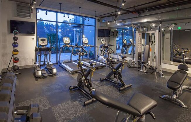 A gym with a variety of equipment including treadmills, weights, and exercise machines.