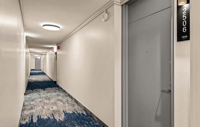 A hallway with a blue carpet and white walls.