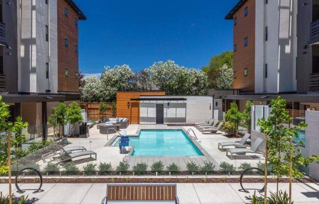 1-Bedroom Apartments in Santa Clara, CA - Santana Terrace - Swimming pool with Lounge Chairs, Beautiful Landscaping, and a Wooden Bench in Front
