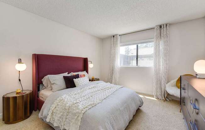 A bedroom with a large bed and a red headboard.