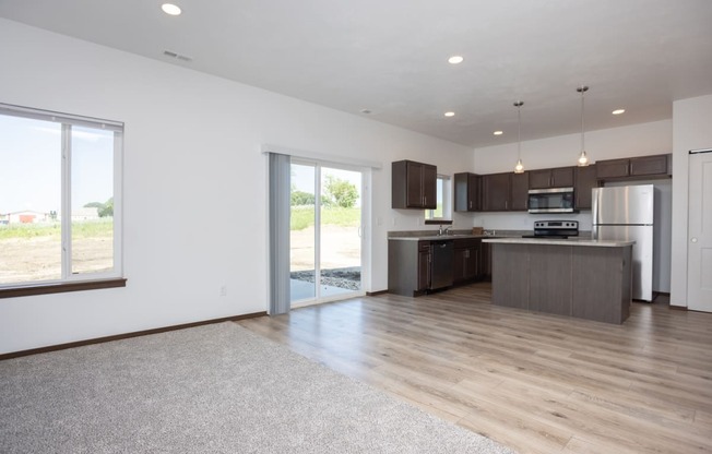 an open kitchen and living room with a sliding glass door to a patio