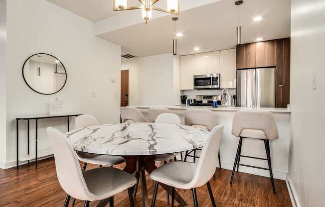 A modern dining room with a round mirror and a marble table.