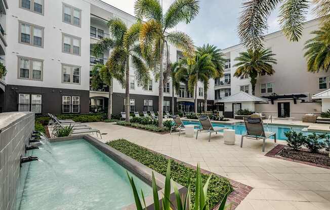 A pool surrounded by palm trees and chairs.