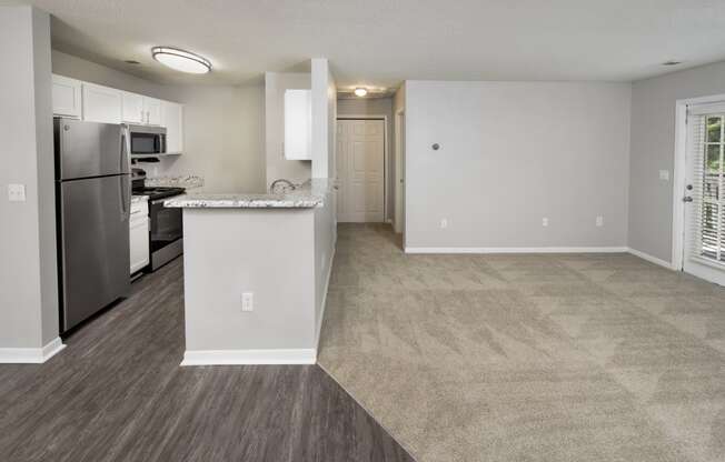 an empty kitchen and living room with a stainless steel refrigerator