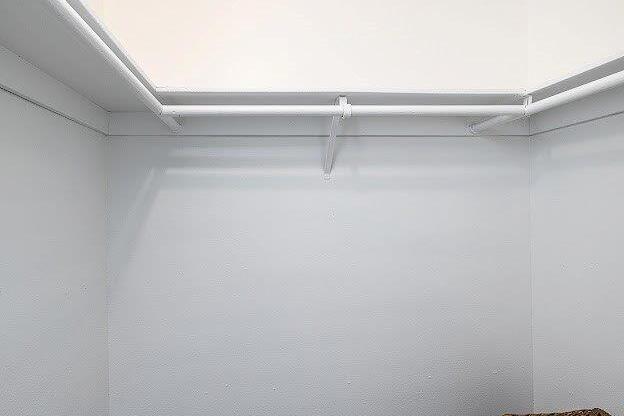A white wall with a white pipe and a brown table.