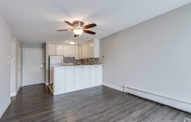 an empty living room and kitchen with a ceiling fan