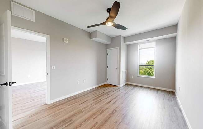 an empty living room with wood floors and a ceiling fan