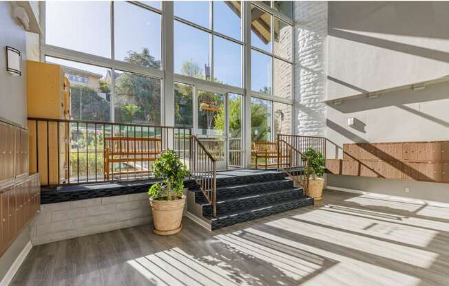 a large glass walled building with a staircase and potted plants in front of it