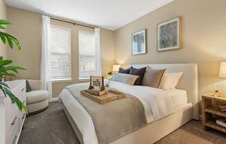 A bedroom with a large bed and a chair.