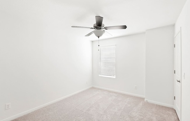 a bedroom with white walls and a ceiling fan