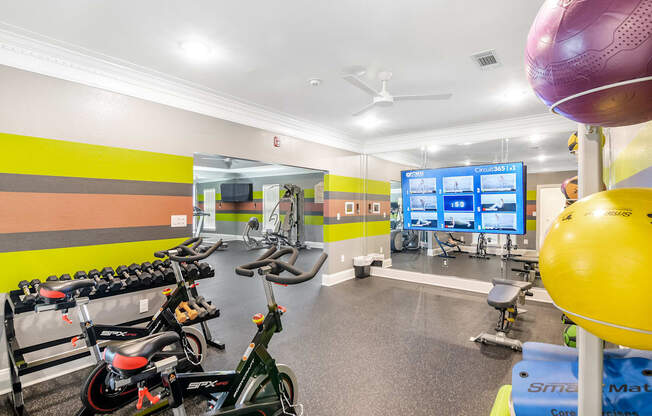 a workout room with bikes and weights and a tv at Avalon Apartment Homes in MS 39759