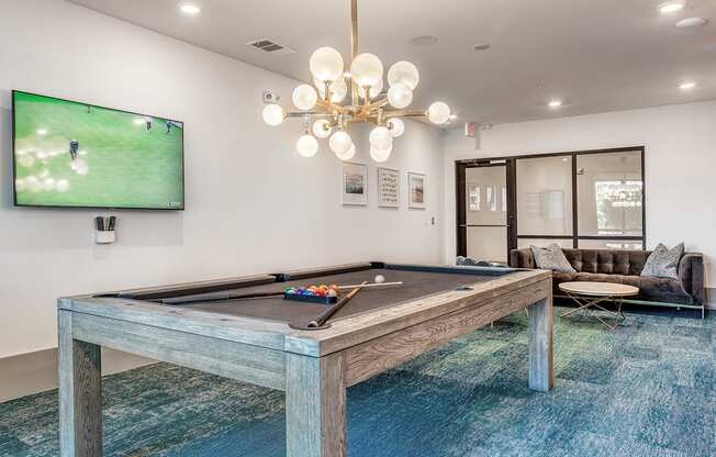 A pool table with a TV showing a game in the background.
