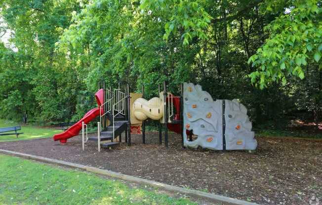 A playground with a slide, a climbing wall, and a seesaw.