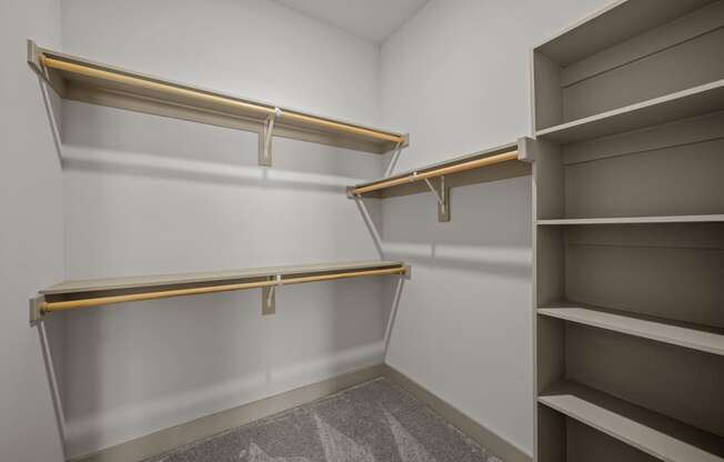 a walk in closet with white walls and empty shelves