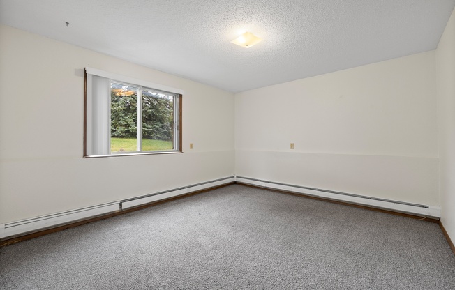 A room with a carpeted floor and a window.