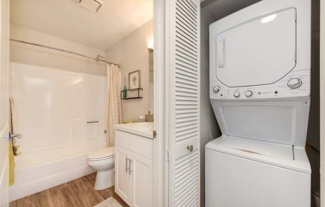 a bathroom with a washer and dryer next to a toilet and a sink