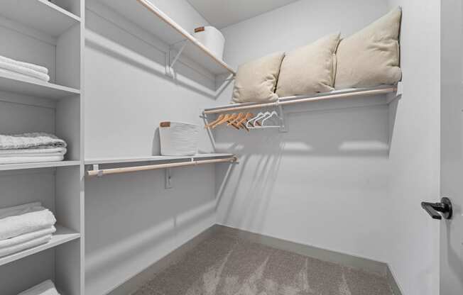 a walk in closet with shelves and a pillow on a shelf
